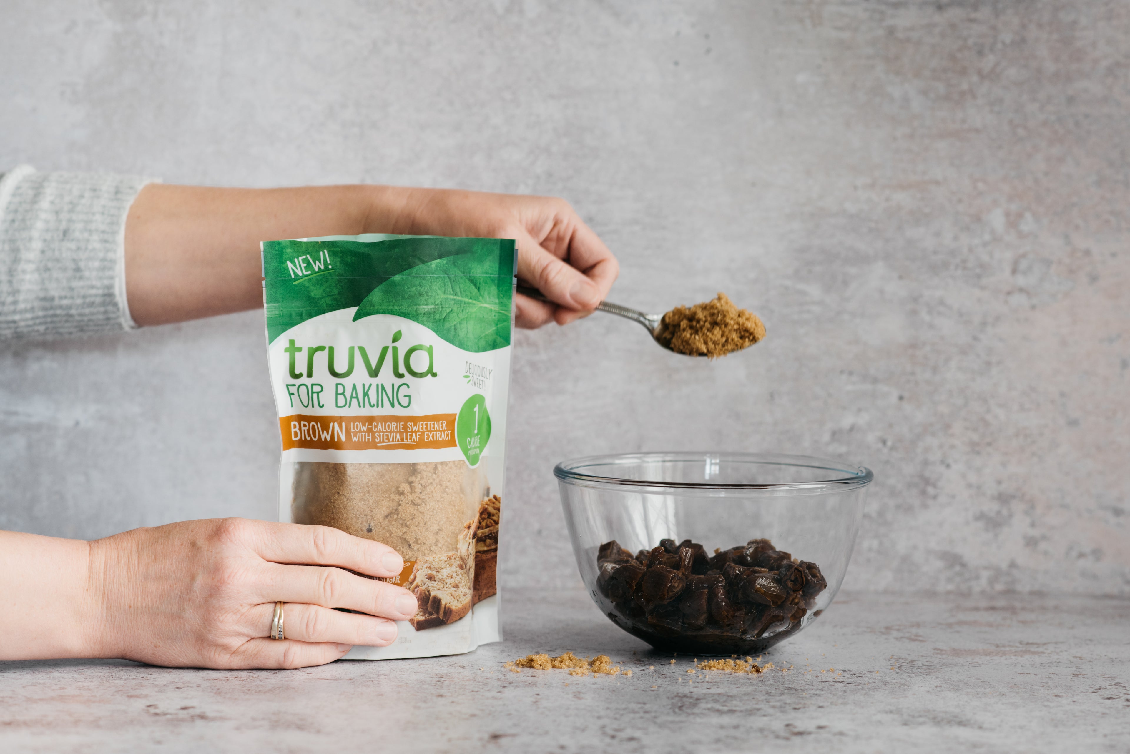 Hand placing a spoonful of Truvia for Baking Brown into the mixing bowl for the No-Bake Millionaire Bites