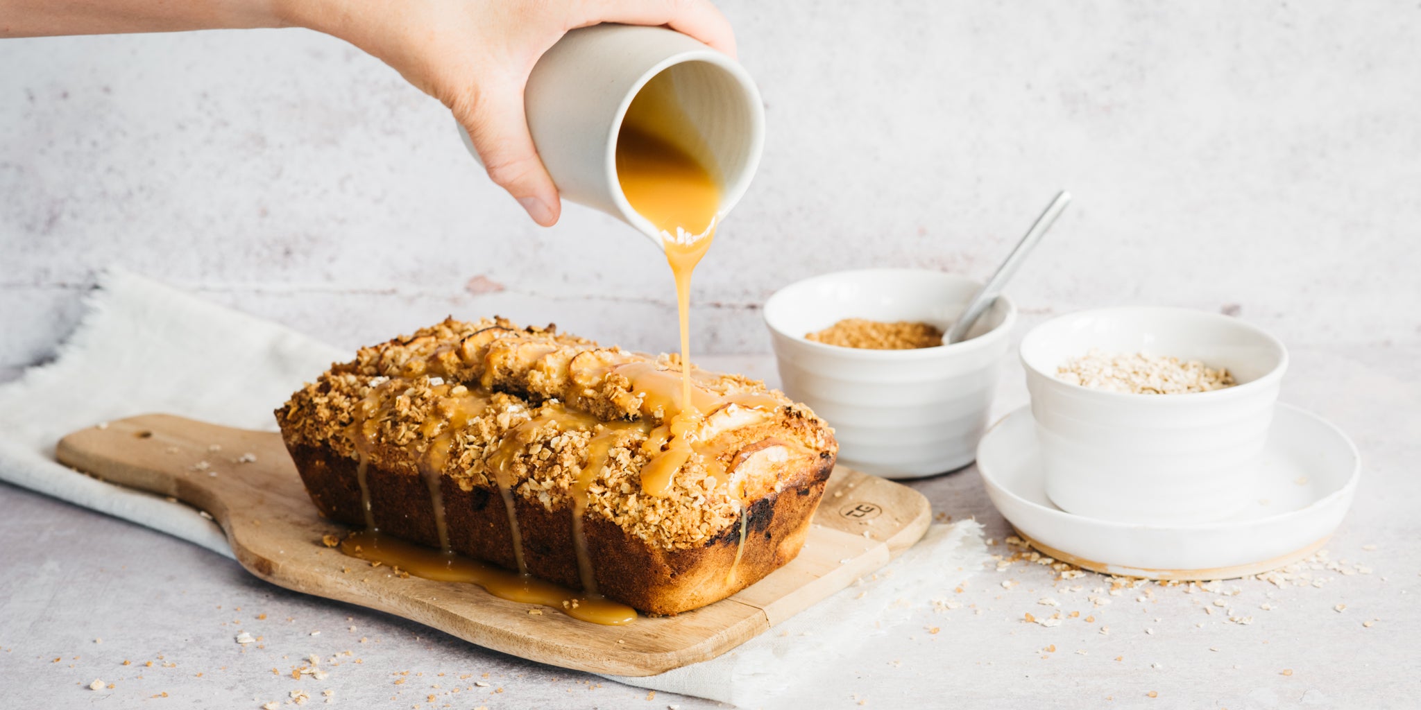 Hand pouring caramel on top of a cake 