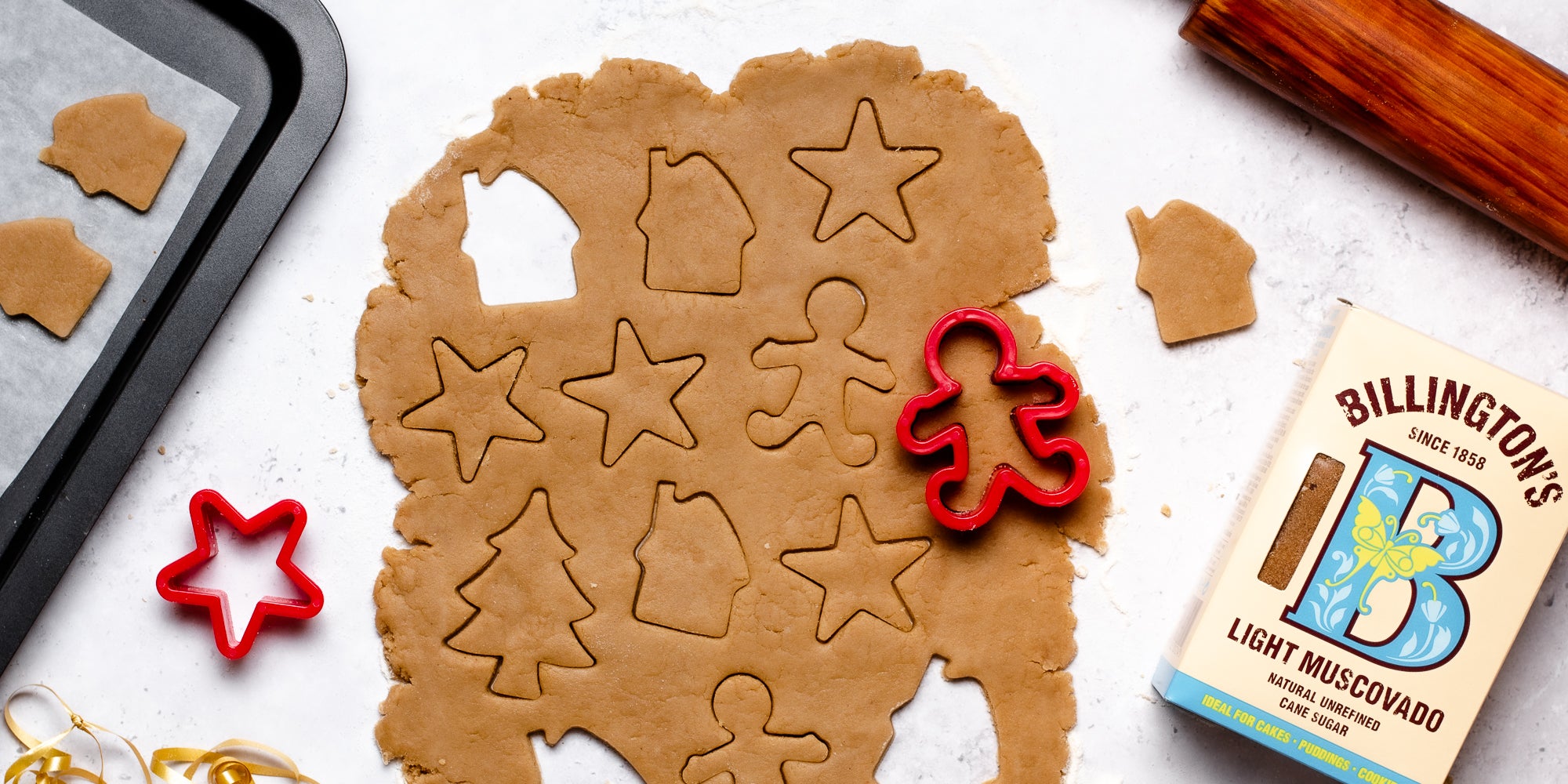 Top down view of a gingerbread man cookie cutter cutting out vegan gingerbread dough
