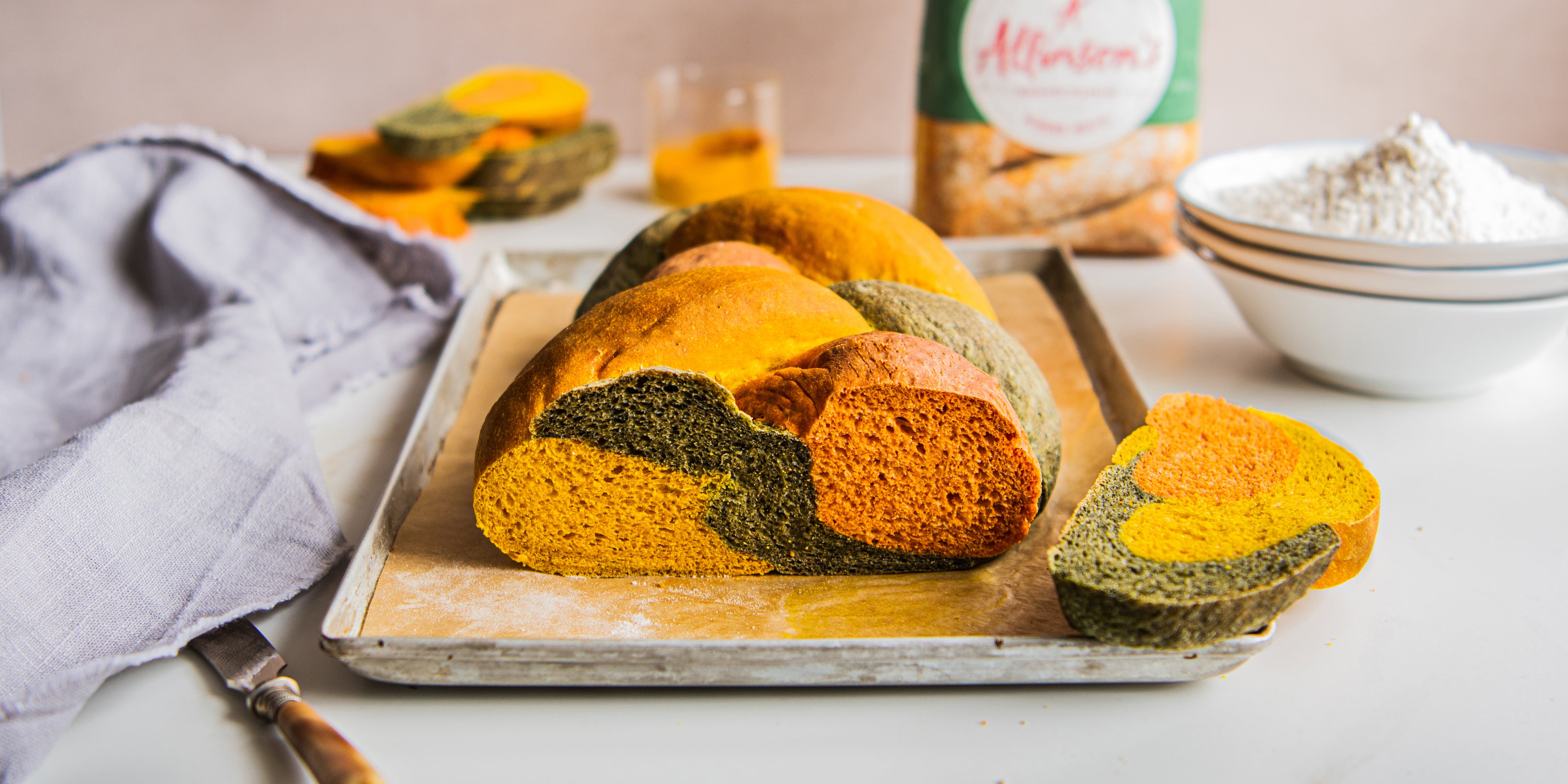 Side on view of a plaited tri colour loaf on a baking tray