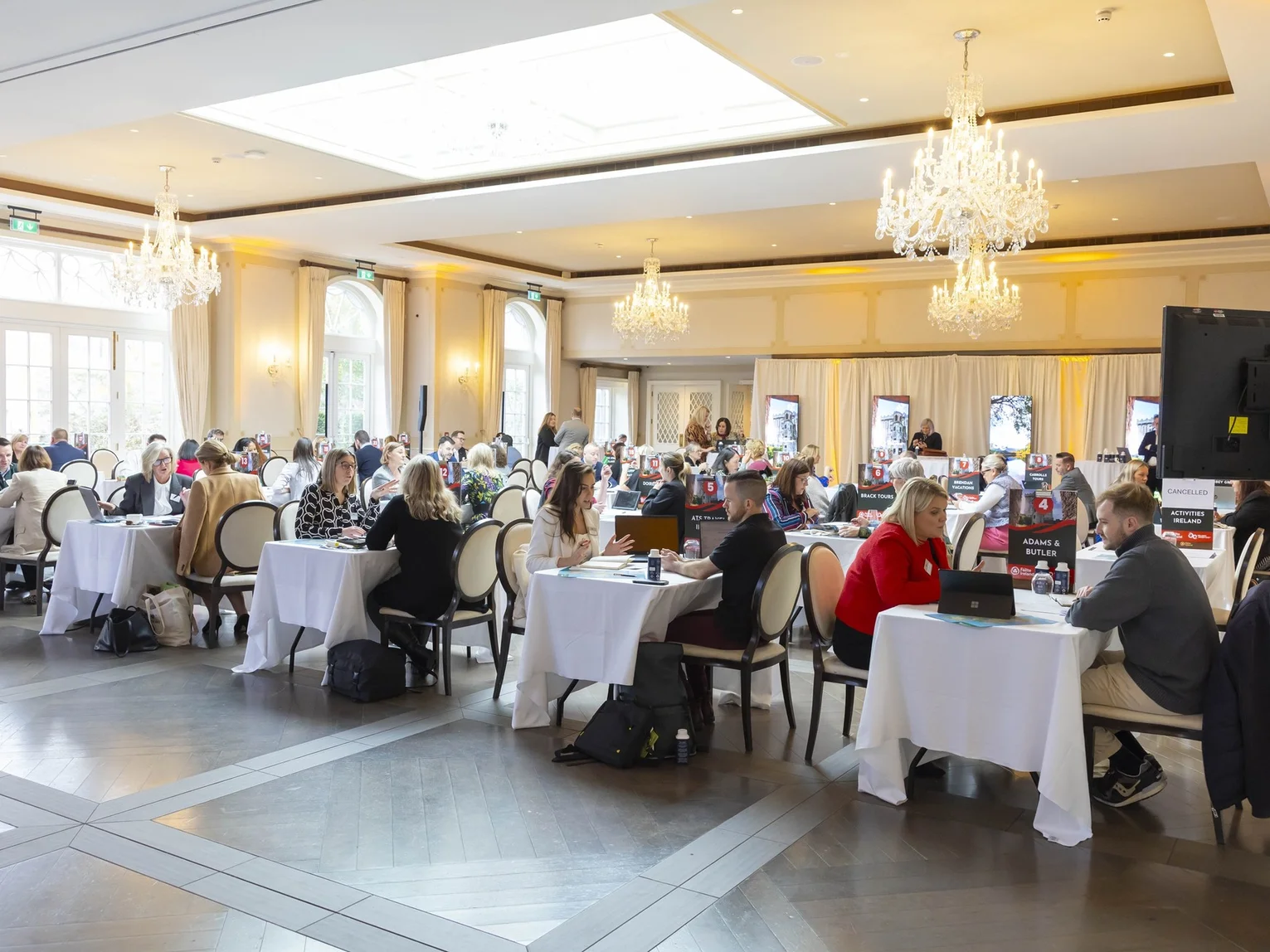 Tourism trade buyers and sellers at round tables in an elegant chandelier-lit ballroom during a workshop event