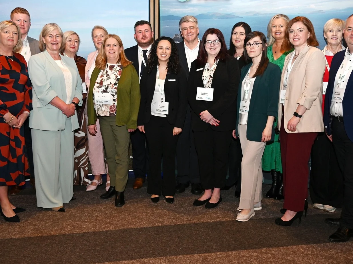 Large group of tourism industry professionals posing for a photo at a conference with a Wild Atlantic Way branded backdrop at IMEX America