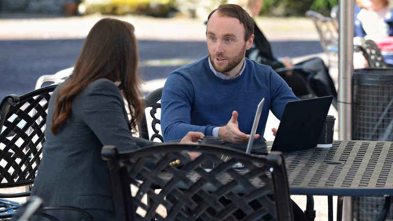 A man and woman sitting at a table with a laptop