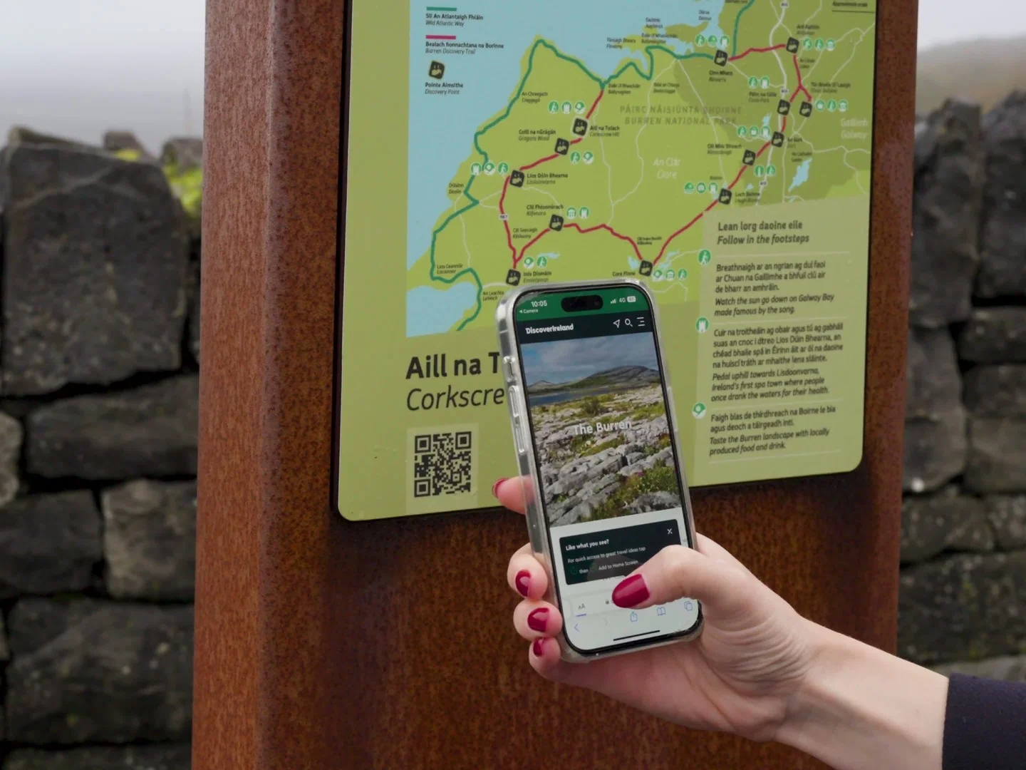 Person holding a smartphone at an outdoor trail sign