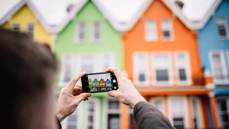 A person holding a phone with a picture of houses in the background