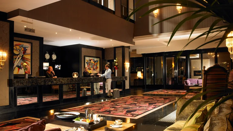 A hotel lobby with a couple of people standing behind the counter