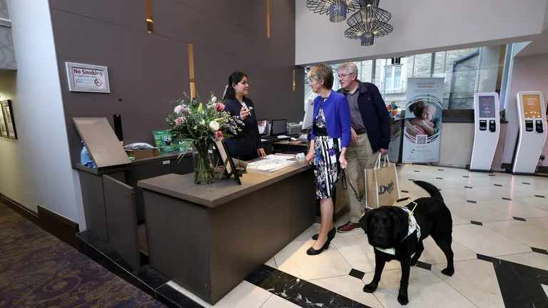 A group of people standing at a reception desk with a dog