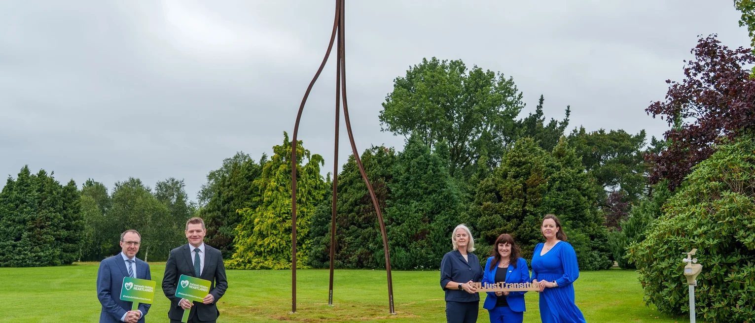 Minister O'Brien and stakeholders pose for photo in front of sculpture.