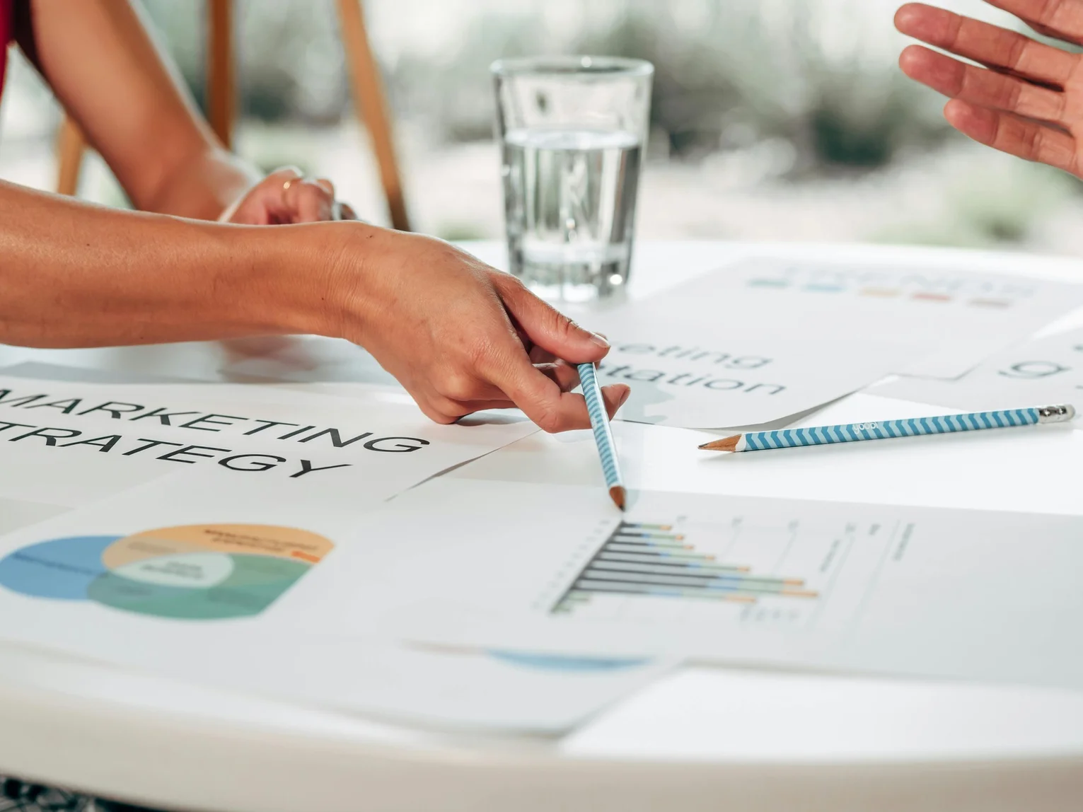 Two people reviewing marketing strategy documents and charts spread out on a table