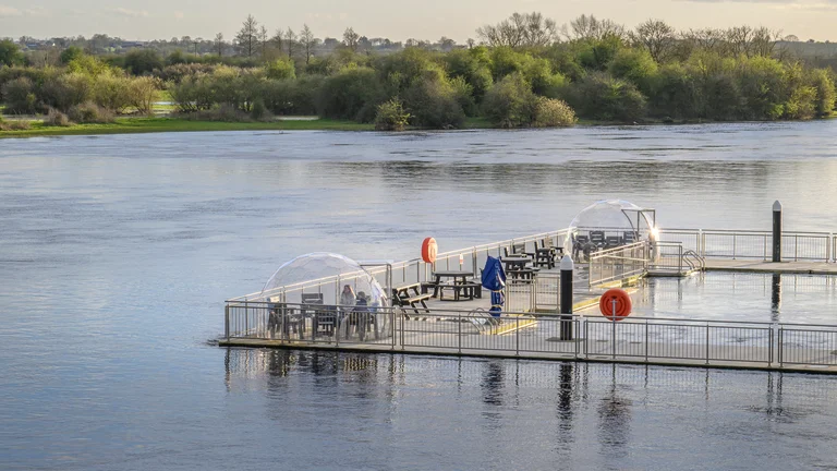 A dock with tables and umbrellas on it