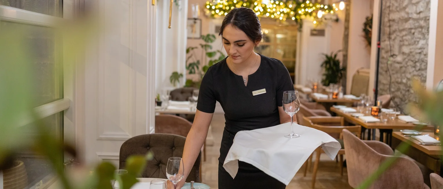 A member of service staff lays a table in a restaurant.
