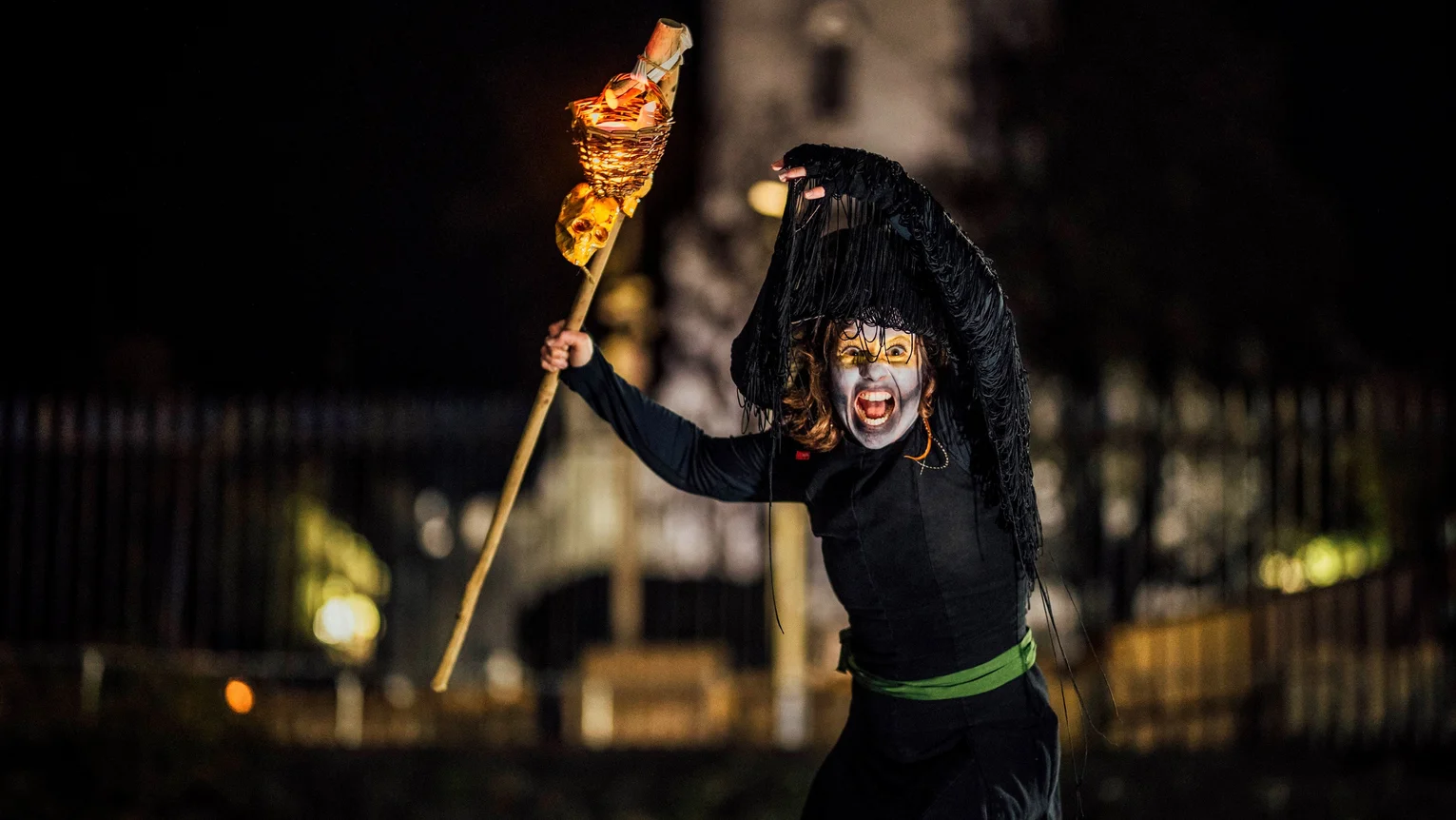 A person in a witch costume holding a torch