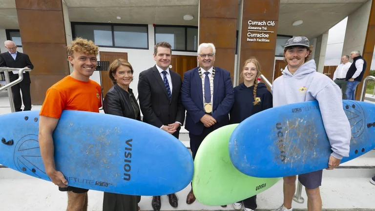Stakeholders and people with surfboards pose for a photo in front of the new water sports centre.