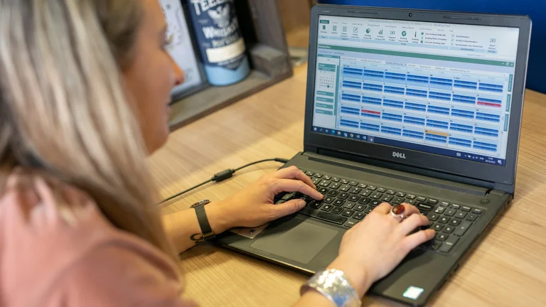 Woman using management software on a laptop at a desk