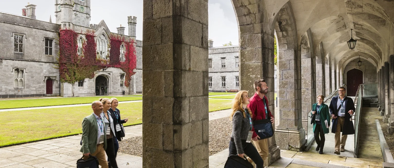 People walk through stone arches from an internal court yard.
