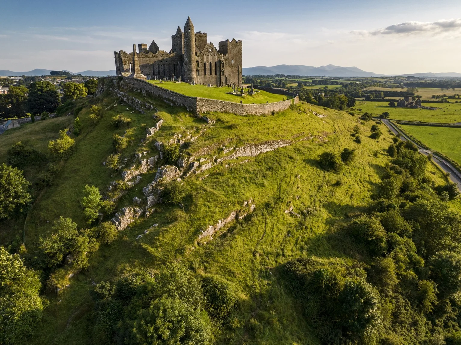Aerial view of the Rock of Cashel, a medieval castle and cathedral on a limestone hill surrounded by green countryside in County Tipperary