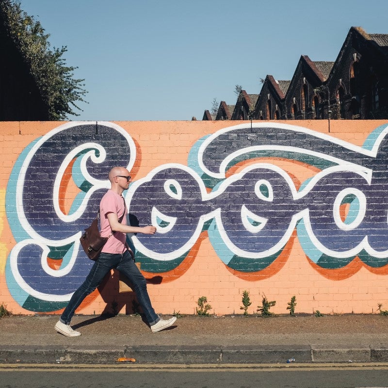 man walking past a mural