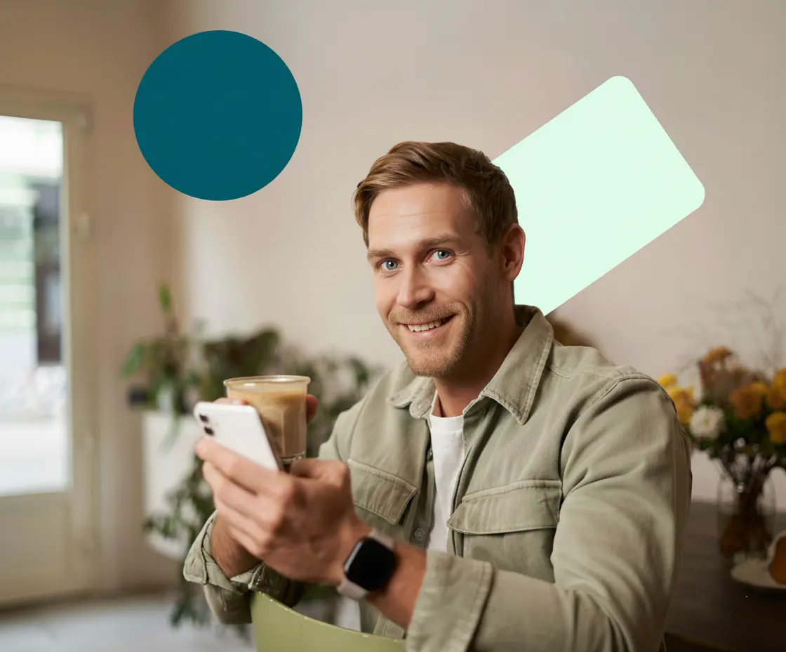 Smiling man with coffee and smartphone.