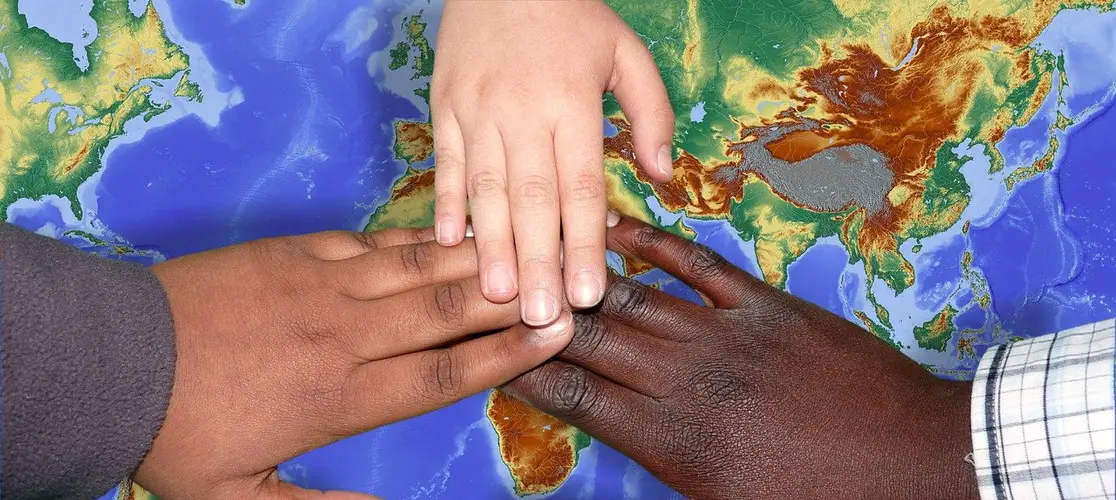 Drei Hände die sich berühren, eine weiß, eine braun, eine dunkelbraun Drei Hände die sich berühren, eine weiß, eine braun, eine dunkelbraun