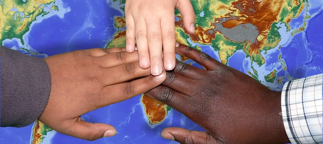 Drei Hände die sich berühren, eine weiß, eine braun, eine dunkelbraun Drei Hände die sich berühren, eine weiß, eine braun, eine dunkelbraun