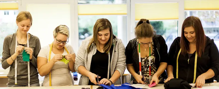 Schülerinnen beim Stoffzuschnitt und nähen von Hand Schülerinnen beim Stoffzuschnitt und nähen von Hand