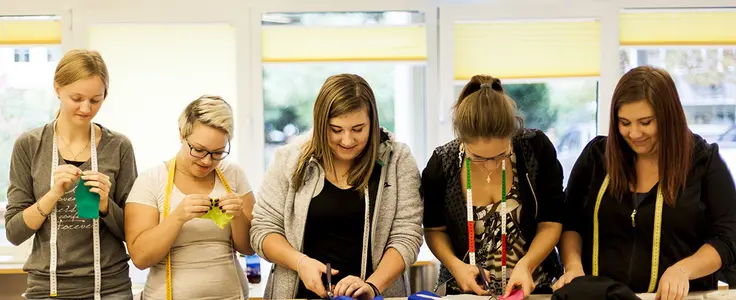 Schülerinnen beim Stoffzuschnitt und nähen von Hand Schülerinnen beim Stoffzuschnitt und nähen von Hand