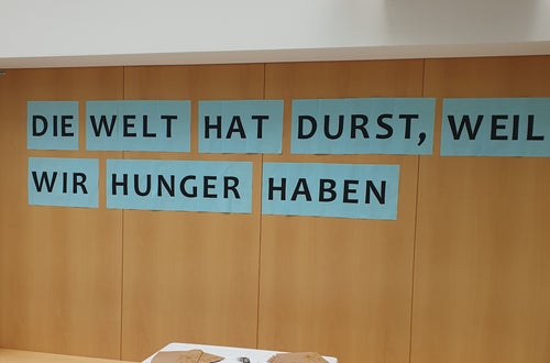 Schriftzug: "Die Welt hat Durst, weil wir Hunger haben". Schriftzug: "Die Welt hat Durst, weil wir Hunger haben".