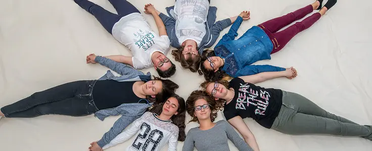 Jugendliche liegen am Boden Kopf an Kopf und halten sich die Hände Jugendliche liegen am Boden Kopf an Kopf und halten sich die Hände