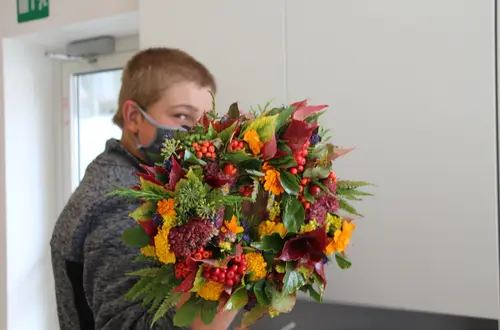 Schüler hält seinen selbst gewundenen Herbstkranz in der Hand Schüler hält seinen selbst gewundenen Herbstkranz in der Hand