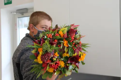 Schüler hält seinen selbst gewundenen Herbstkranz in der Hand Schüler hält seinen selbst gewundenen Herbstkranz in der Hand