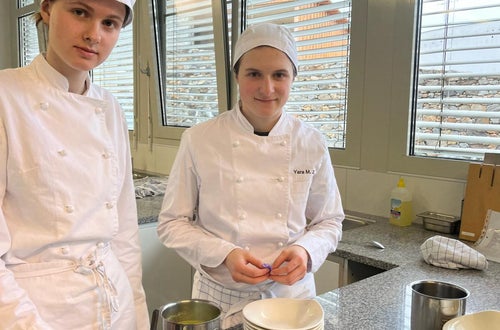 Zwei Schülerinnen beim Garnieren der Suppe mit frischen Blüten Zwei Schülerinnen beim Garnieren der Suppe mit frischen Blüten