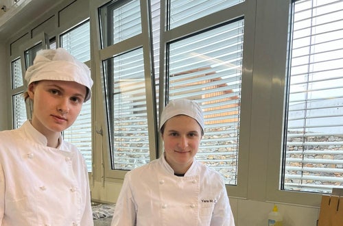 Zwei Schülerinnen beim Garnieren der Suppe mit frischen Blüten Zwei Schülerinnen beim Garnieren der Suppe mit frischen Blüten