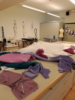 Nährraum: Im Vordergrund der Zuschneidetisch mit verschiedenen Stoffen Nährraum: Im Vordergrund der Zuschneidetisch mit verschiedenen Stoffen