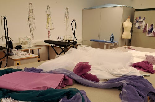 Nährraum: Im Vordergrund der Zuschneidetisch mit verschiedenen Stoffen Nährraum: Im Vordergrund der Zuschneidetisch mit verschiedenen Stoffen