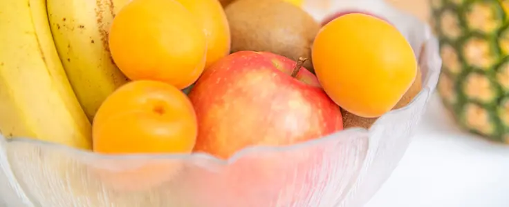 Obstschüssel mit Marillen, Apfel, Kiwi, Bananen und einer Ananas Obstschüssel mit Marillen, Apfel, Kiwi, Bananen und einer Ananas
