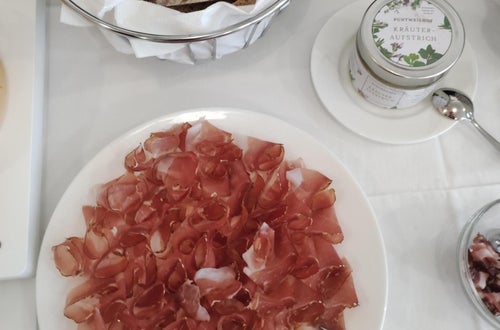 Im Vordergrund steht ein Speckteller und im Hintergrund geschnittenes Brot Im Vordergrund steht ein Speckteller und im Hintergrund geschnittenes Brot