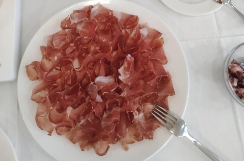 Im Vordergrund steht ein Speckteller und im Hintergrund geschnittenes Brot Im Vordergrund steht ein Speckteller und im Hintergrund geschnittenes Brot