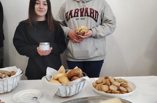 Zwei Schülerinnen halten bäuerlichen Produkten in ihren Händen und im Vordergrund steht eine Käseplatte und Brot. Zwei Schülerinnen halten bäuerlichen Produkten in ihren Händen und im Vordergrund steht eine Käseplatte und Brot.