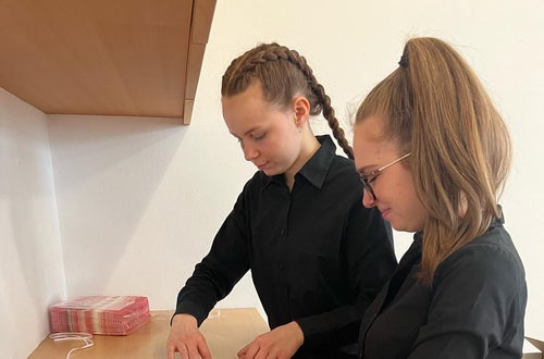 Schülerinnen bei der Serviettenfaltung Schülerinnen bei der Serviettenfaltung