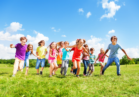 dzieci w wieku szkolnym biegna po łące, bezpieczna zabawa dzieci i młodzieży