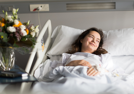 Smiling woman laying in the hospital bed. 