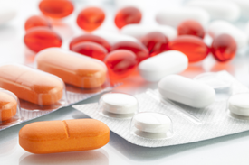 blistry z tabletkami - czerwone pigułki, pomarańczowe pigułki i białe tabletki
