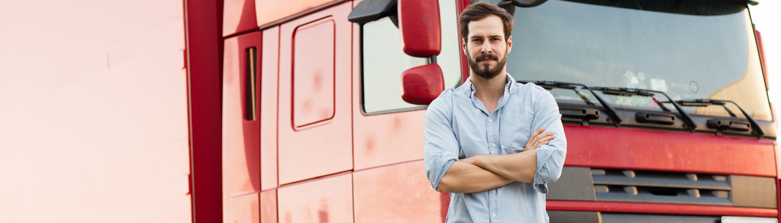mężczyzna w koszuli na tle czerwonej ciężarówki, kierowca ciężarówki w firmie transportowej
