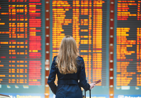 odwołany lot na wyjazd turystyczny, kobieta na tle tablicy na lotnisku