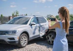 Žena si fotí rozbité auto.