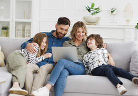 Happy family sitting together in living room using a computer 