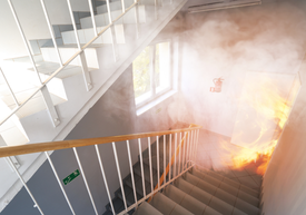 pożar po wybuchu w mieszkaniu, ogień i dym na klatce schodowej