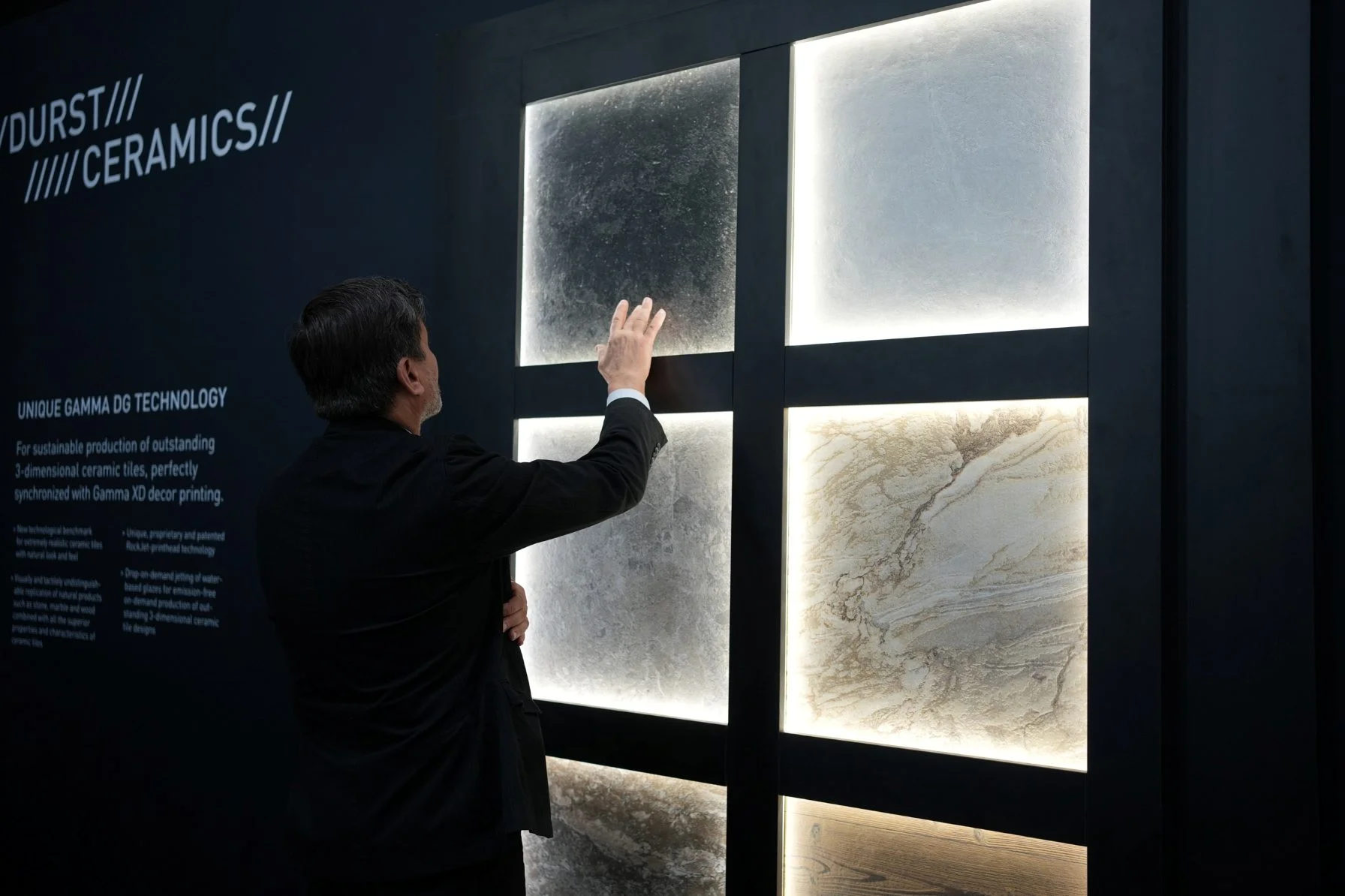 Man in suit touching a display surface showing different tile prints