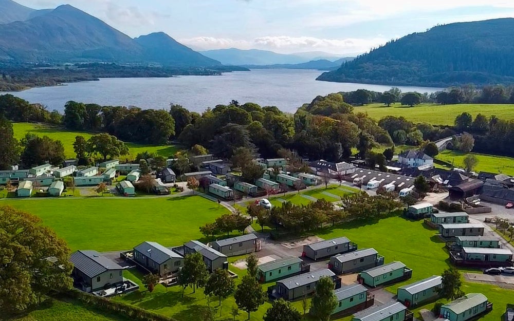 Ariel shot of a holiday park by a river side and mountains.