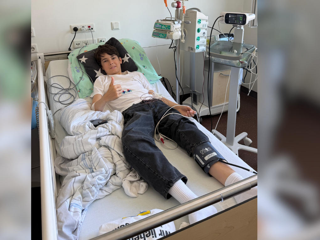 Ein Junge liegt in einem Krankenhausbett und zeigt den Daumen nach oben. Ein Junge liegt in einem Krankenhausbett und zeigt den Daumen nach oben.
